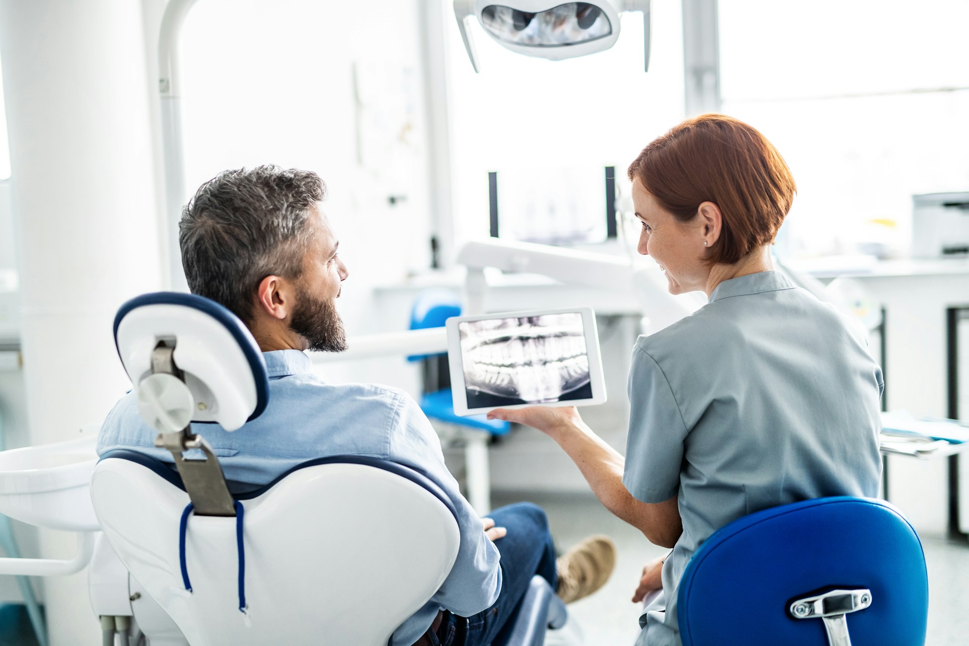 Zahnärztin zeigt einem Patienten eine Röntgenaufnahme auf dem Tablet (Platzhalterfoto)